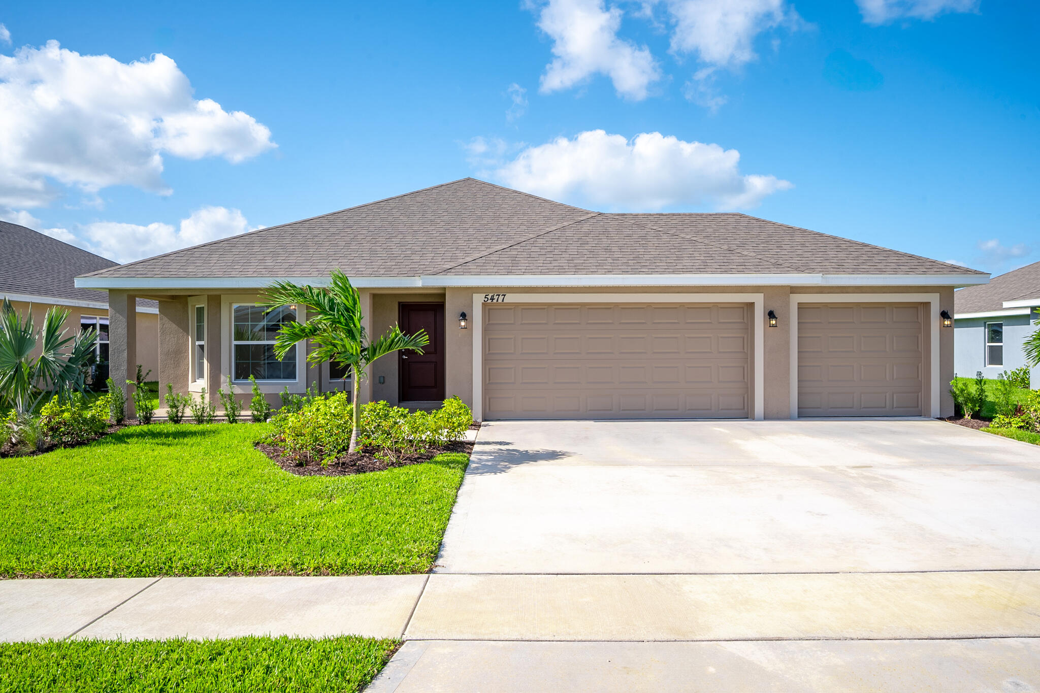 a front view of a house with a yard and potted plants