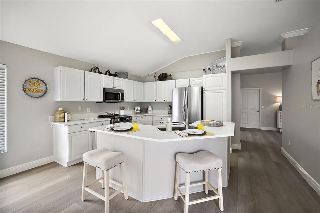 a kitchen with stainless steel appliances kitchen island granite countertop a table chairs cabinets and wooden floor