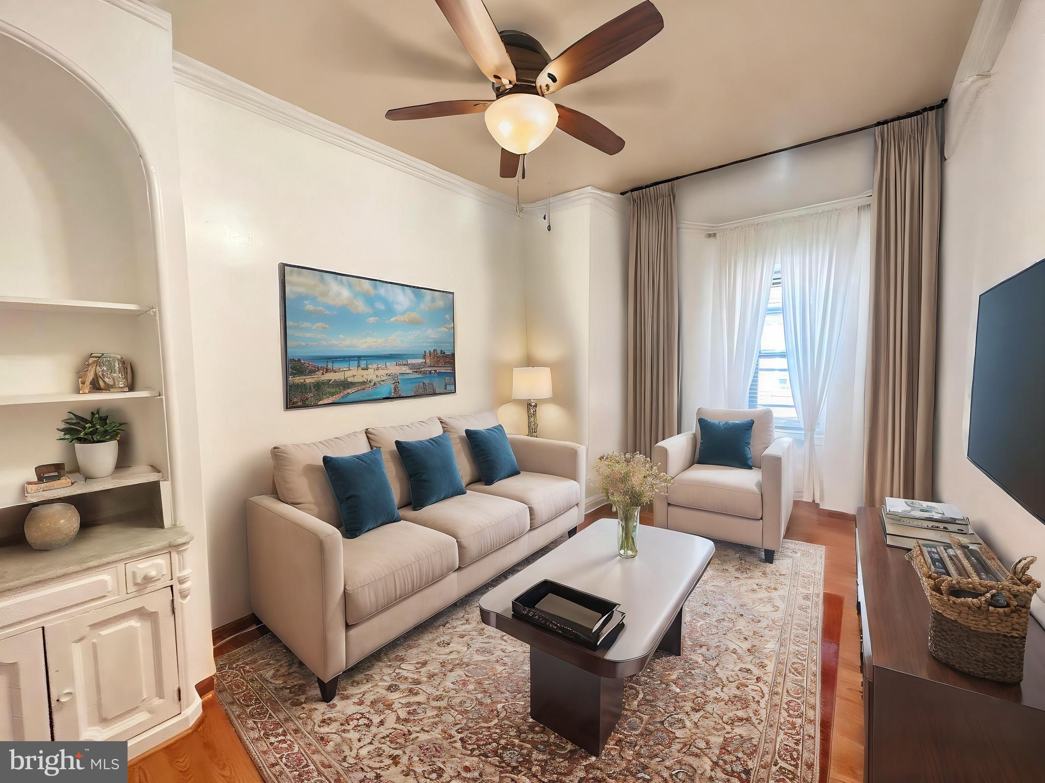 a living room with furniture a flat screen tv and a window