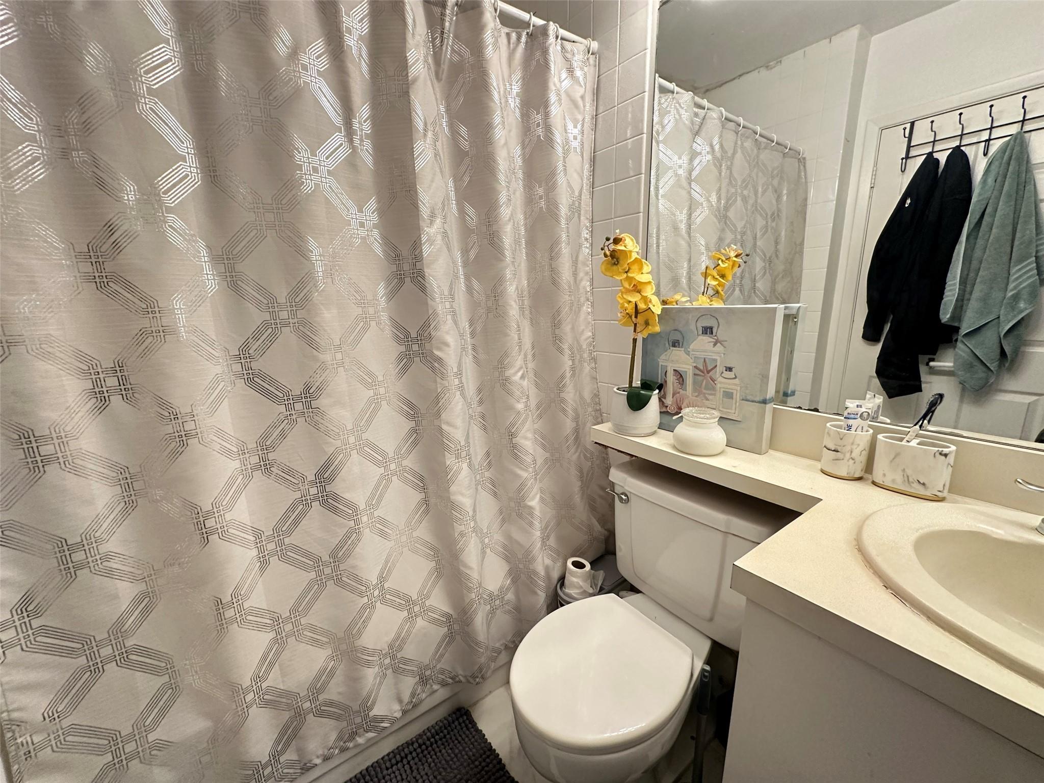 Bathroom with vanity, curtained shower, and toilet