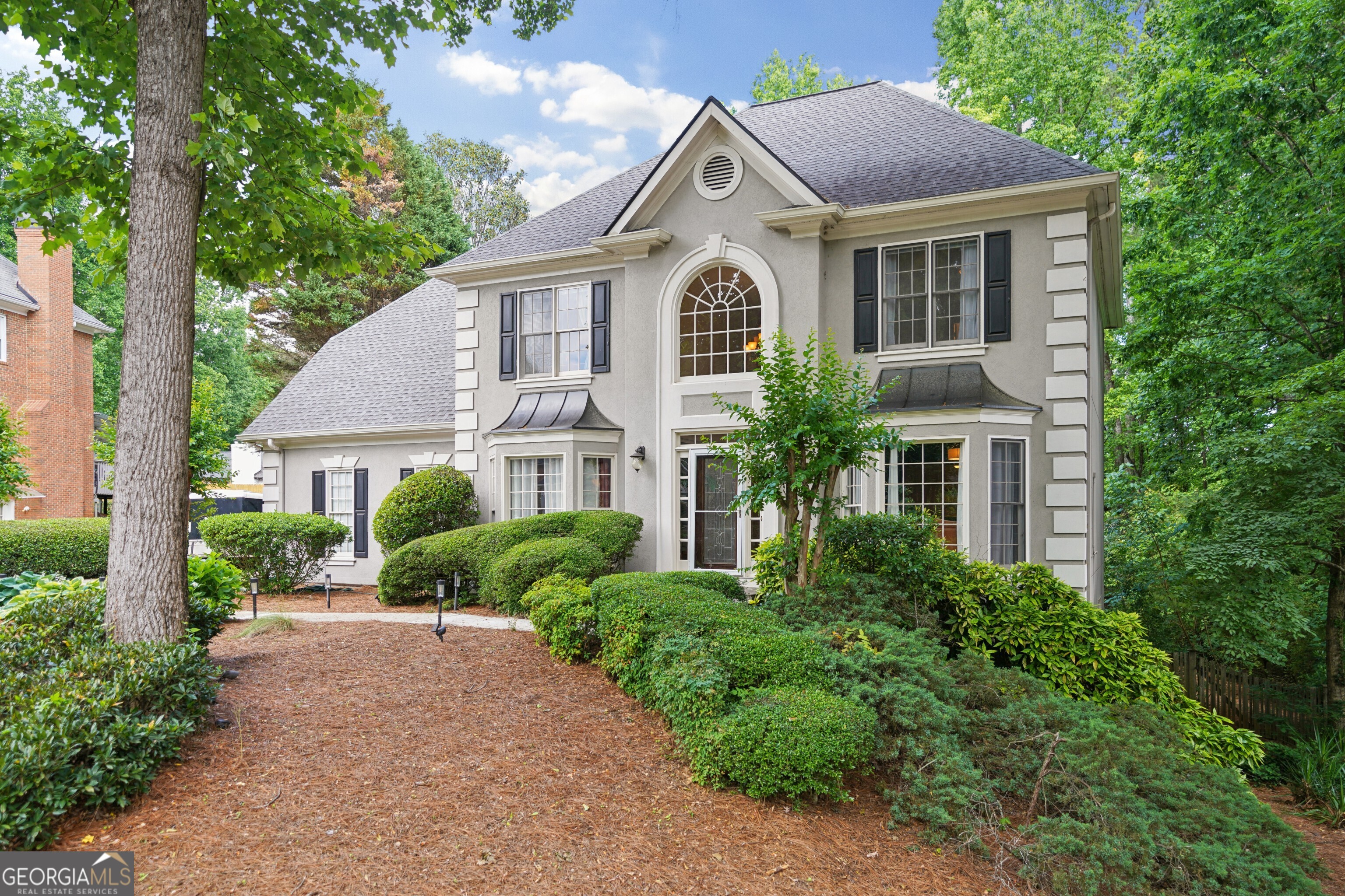 a front view of a house with a yard and potted plants