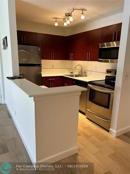 a kitchen with kitchen island stainless steel appliances a sink and a stove