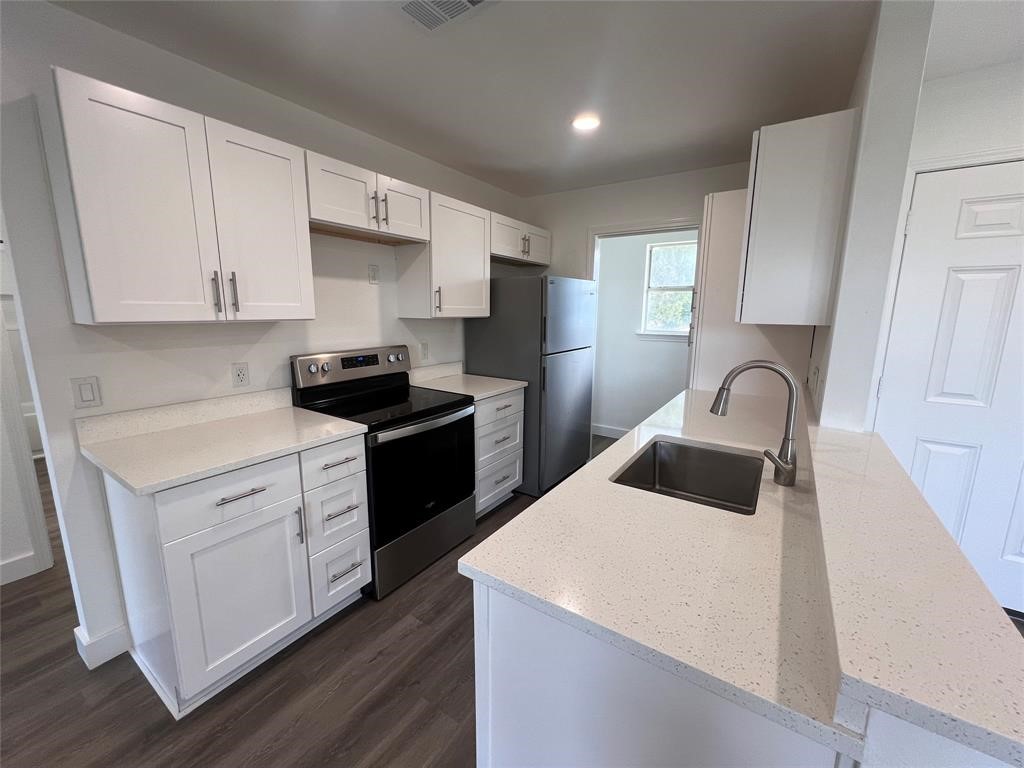 a kitchen with a sink white cabinets and black appliances