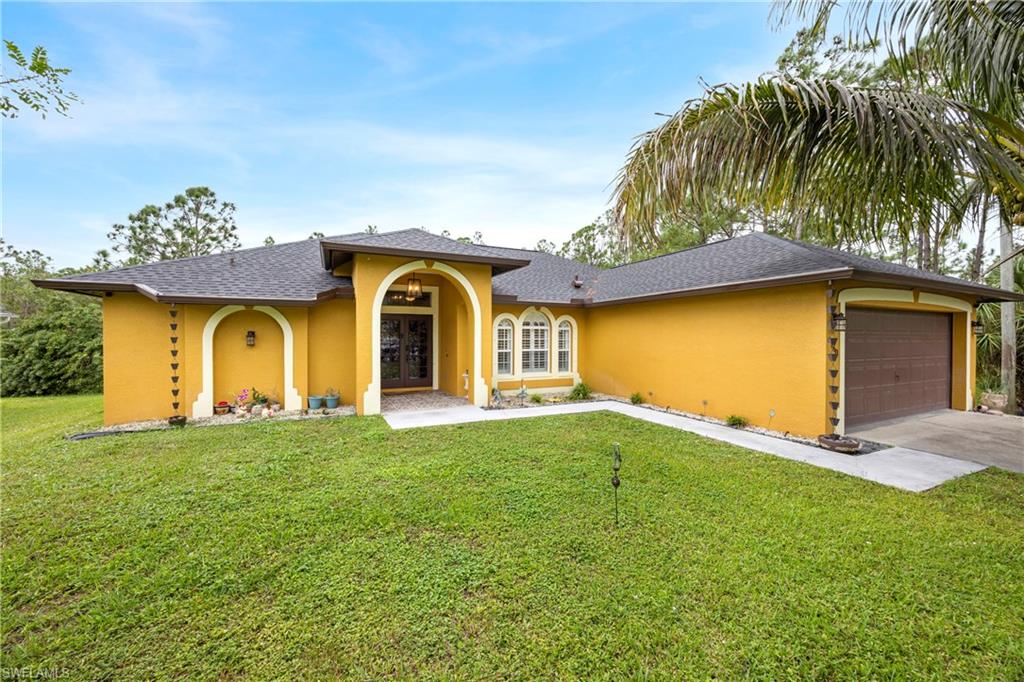 View of front of house featuring a front lawn, a garage, and french doors