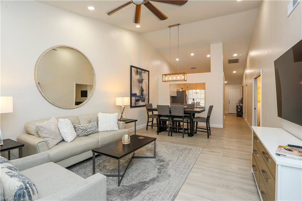 a living room with furniture kitchen view and a wooden floor