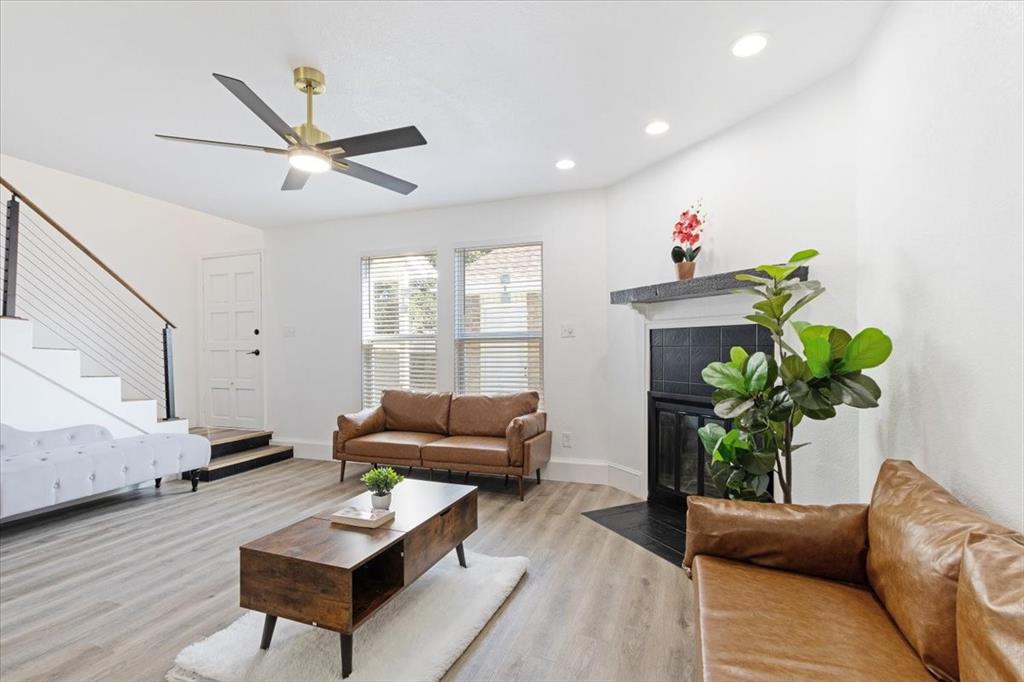 Living room with ceiling fan, a fireplace, and light wood-type flooring