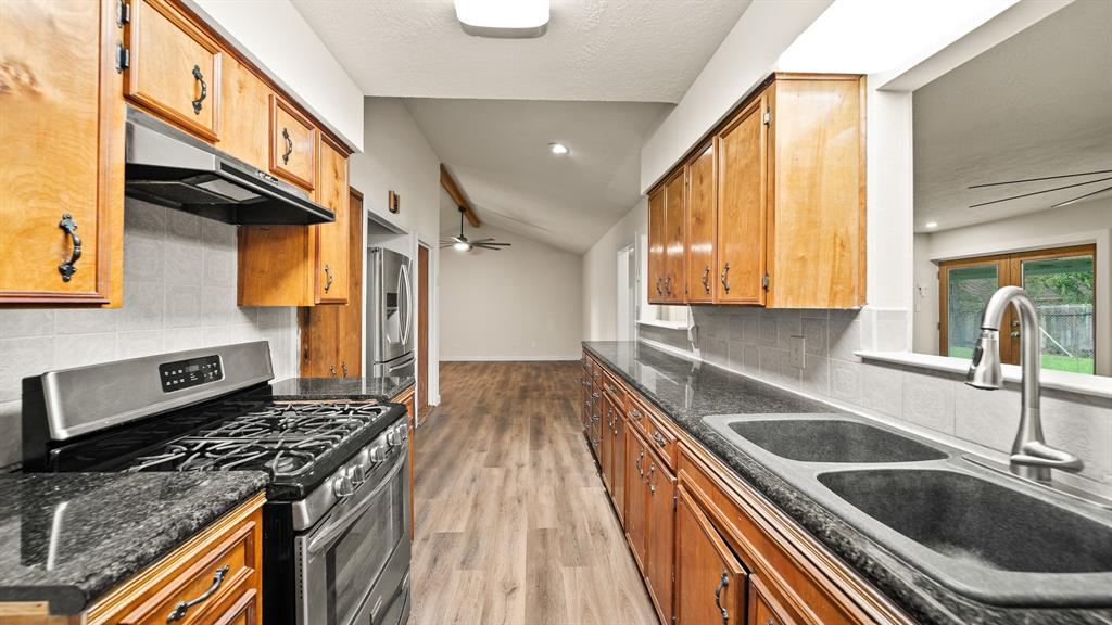 a kitchen with granite countertop a sink a stove and wooden cabinets