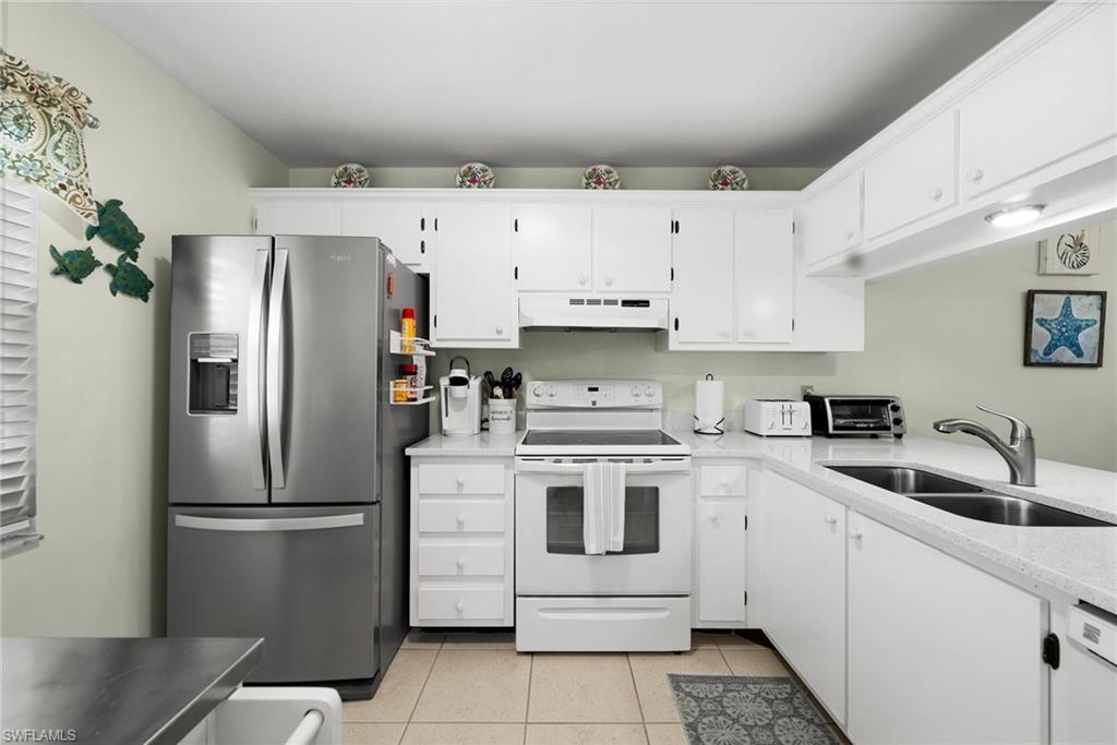 a kitchen with stainless steel appliances granite countertop a refrigerator sink and white cabinets