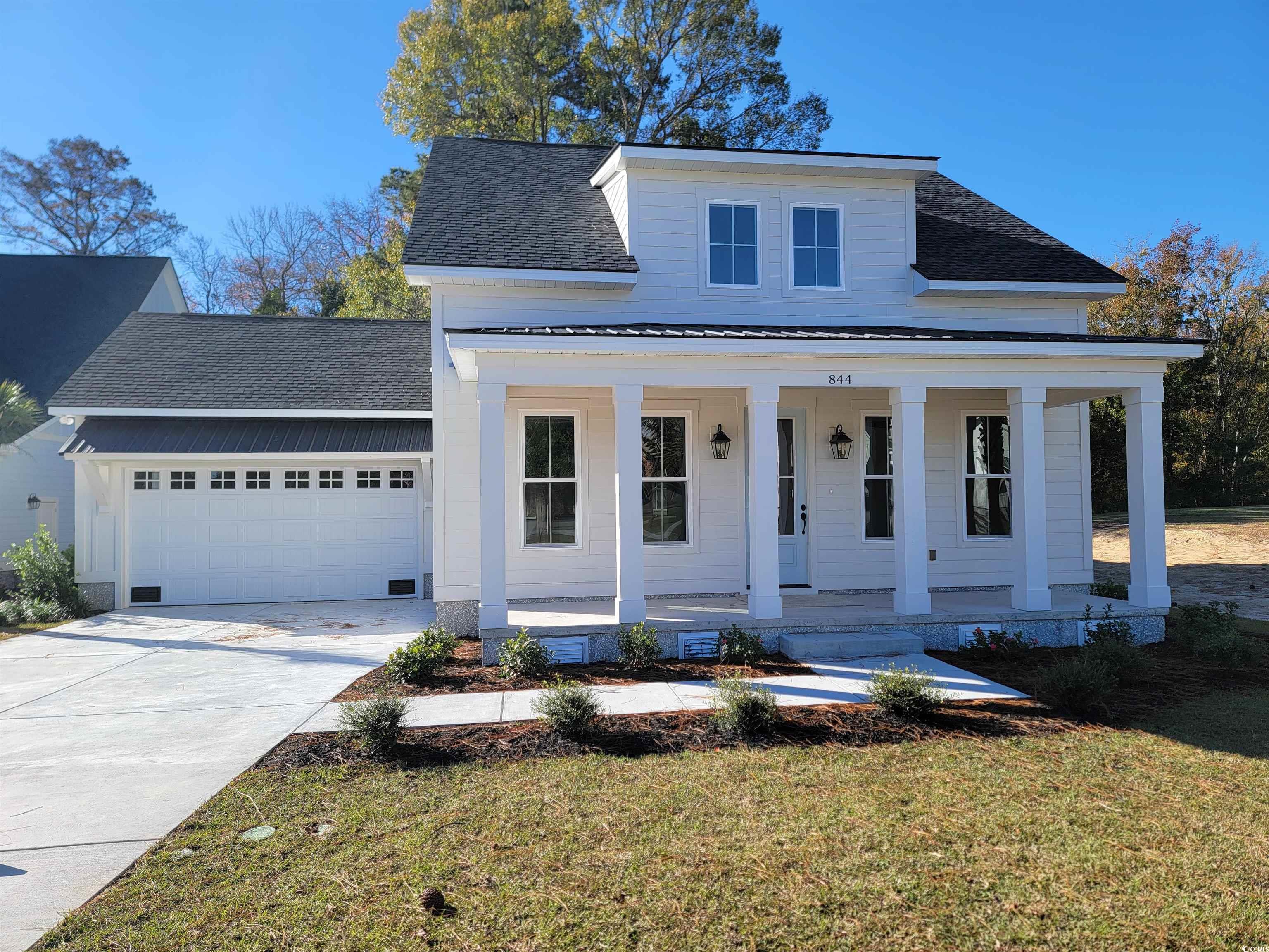 View of front of property with a porch, a garage,