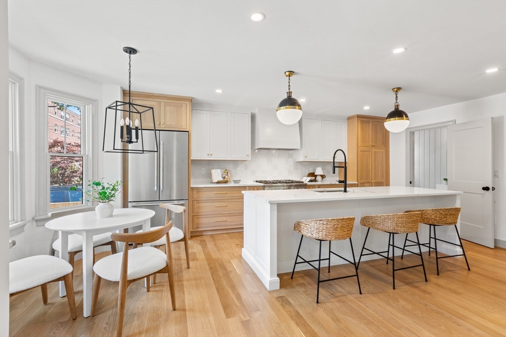 a kitchen with stainless steel appliances kitchen island granite countertop a dining table chairs and white cabinets