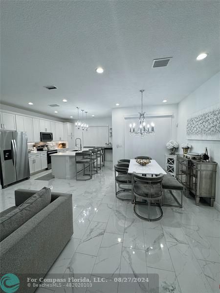 a living room with furniture kitchen view and a chandelier