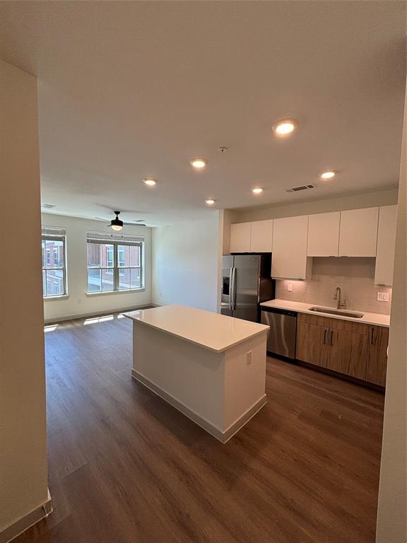 a large white kitchen with kitchen island a sink dishwasher a stove and a refrigerator with wooden floor