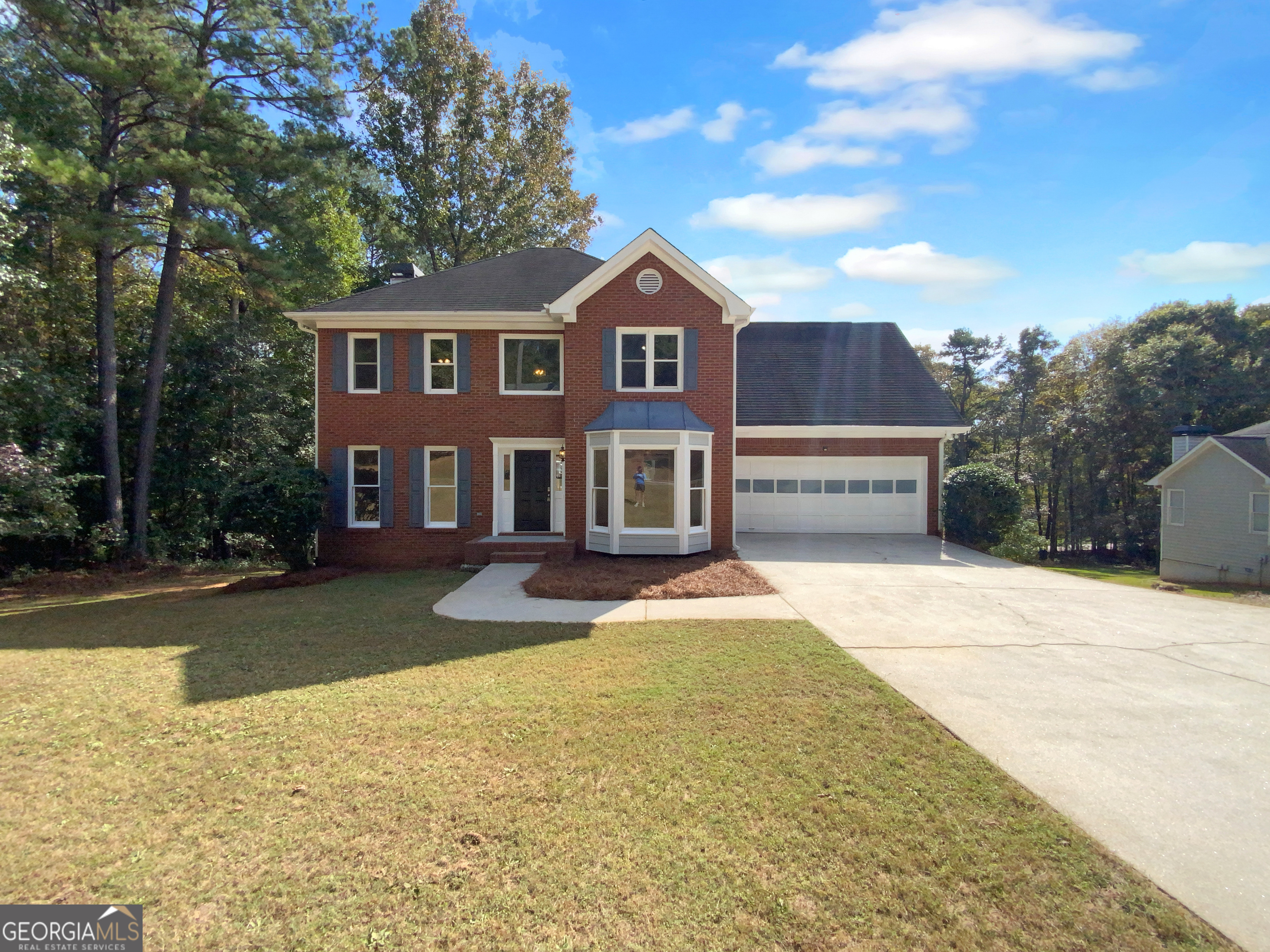 a front view of a house with yard and parking