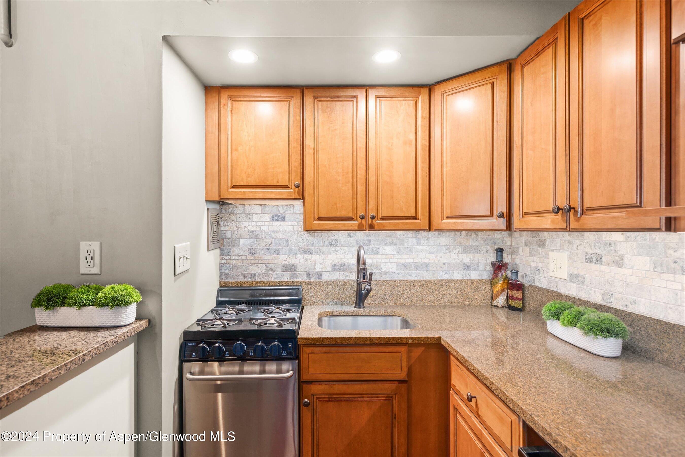 a kitchen with a stove a sink and a wooden cabinets