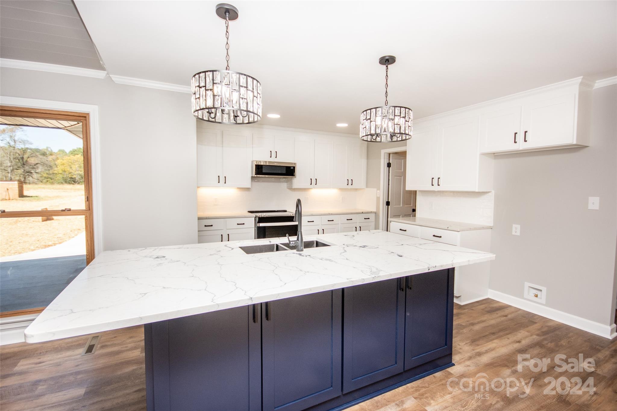 a kitchen with a sink a chandelier and wooden floor