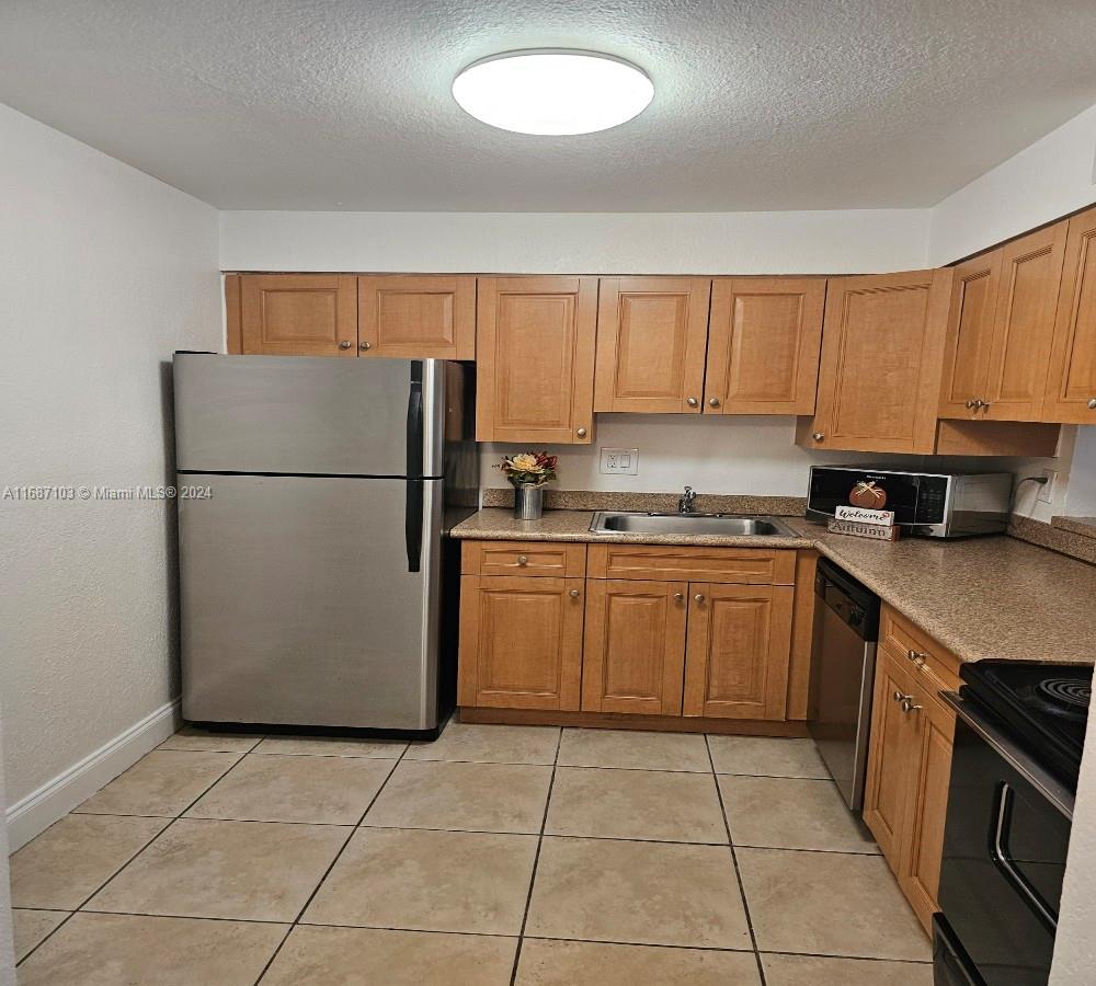 a kitchen with a refrigerator a stove top oven a sink and cabinets