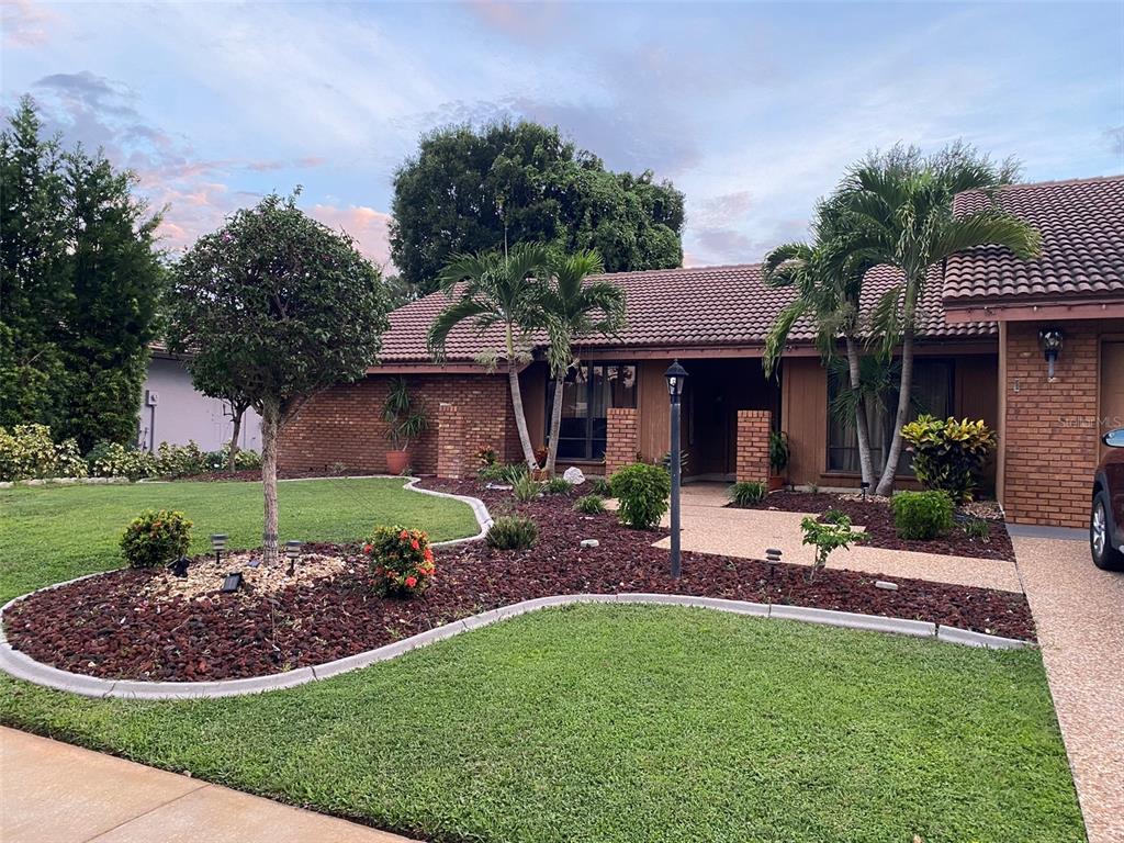 a view of a house with a yard potted plants and a bench