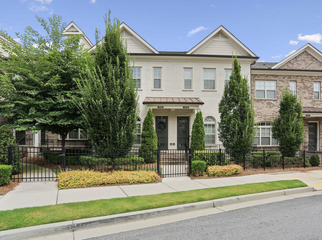 a view of a white house with a yard plants and large tree