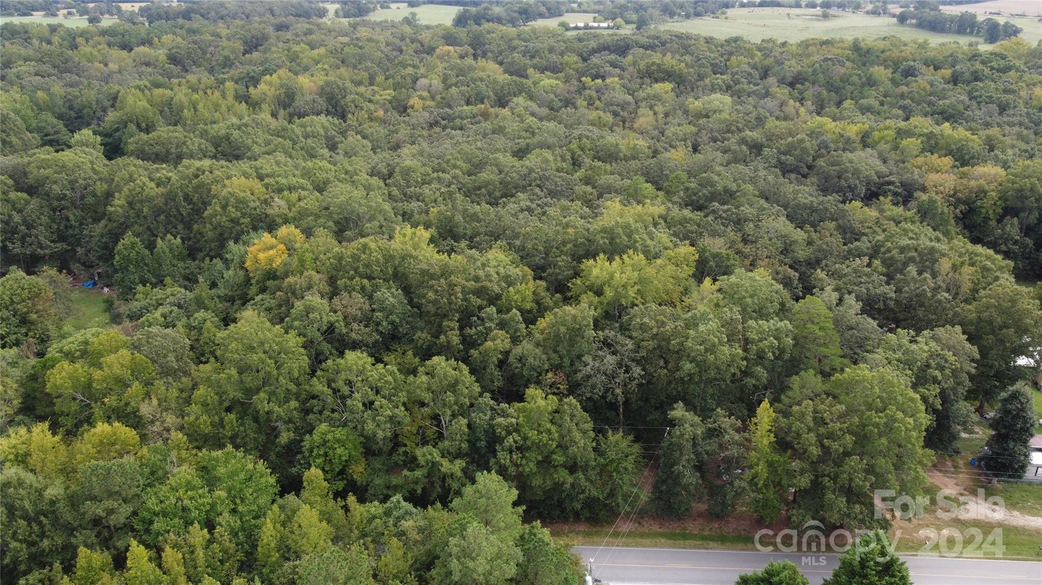 an aerial view of residential house with outdoor space and trees all around