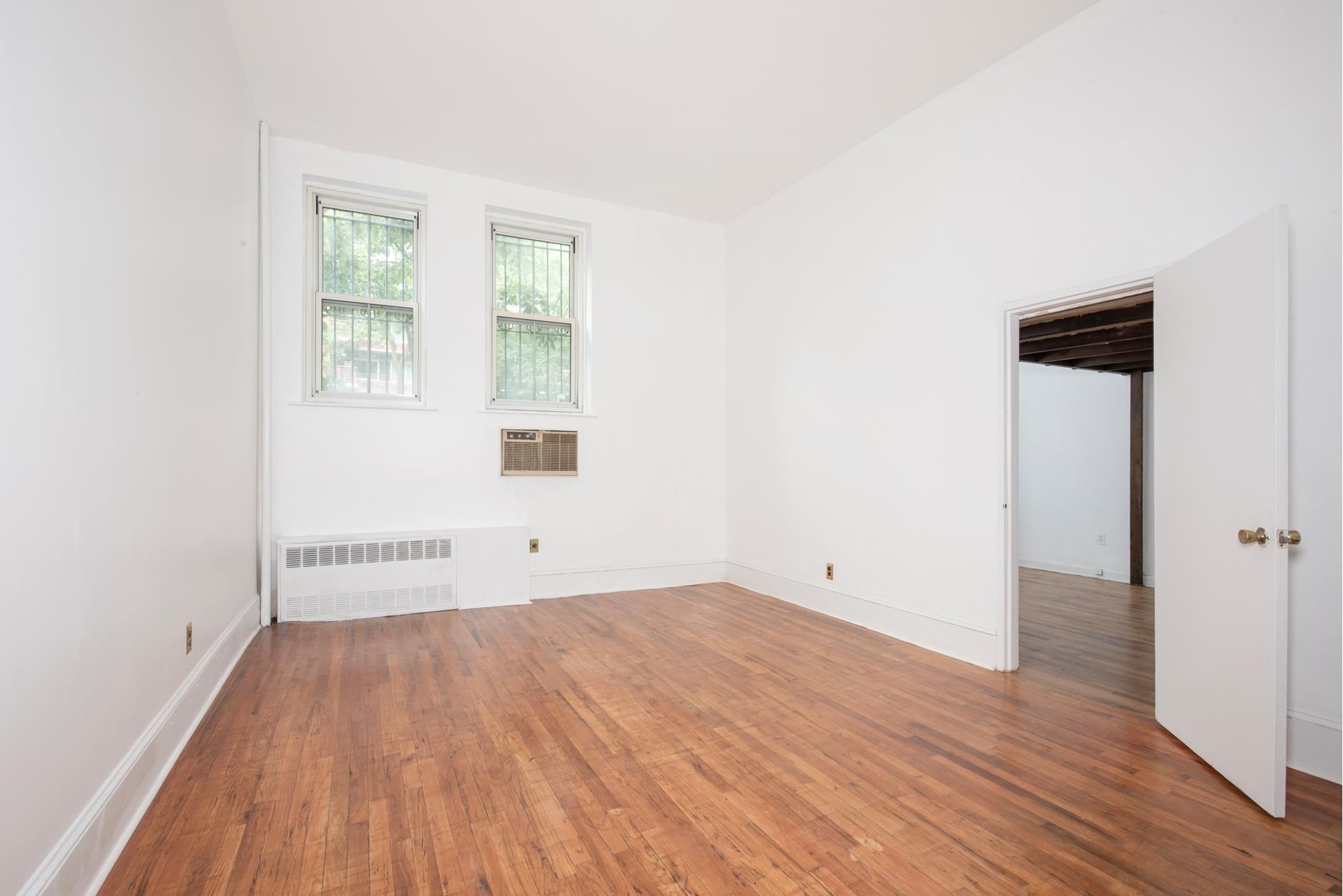 an empty room with wooden floor and windows