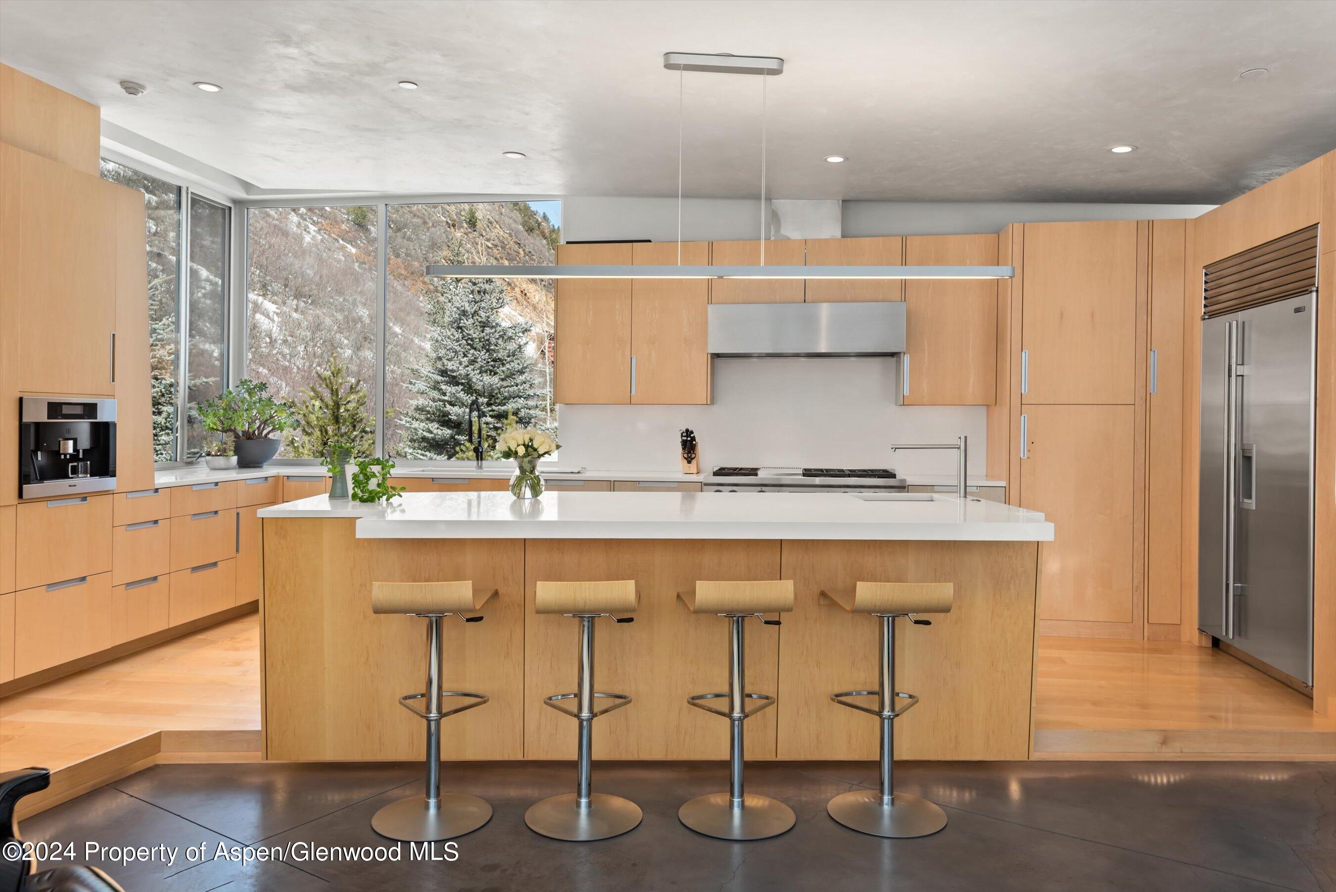 a kitchen with stainless steel appliances kitchen island granite countertop a table chairs in it and wooden floors