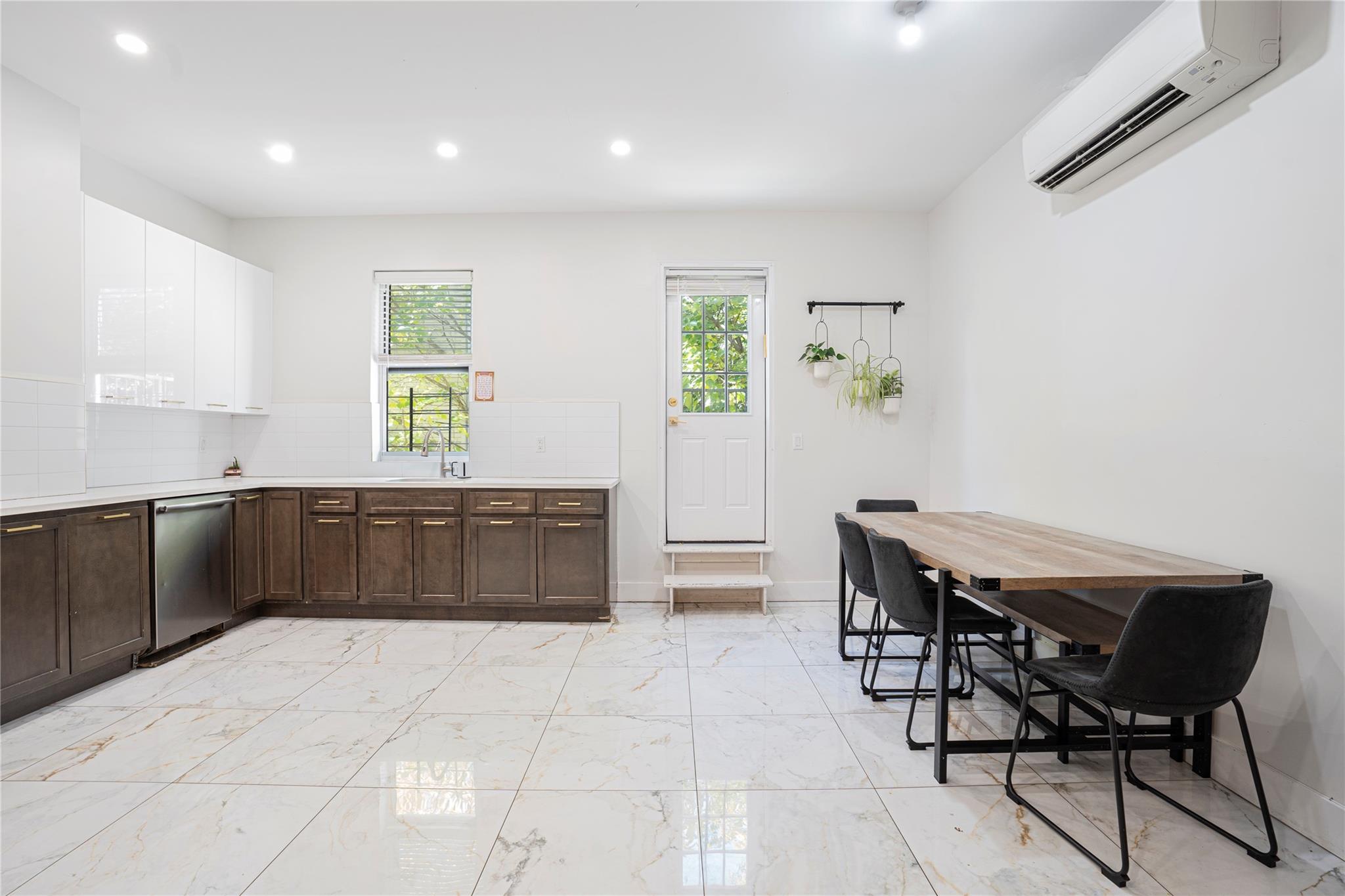 Kitchen featuring a wall mounted air conditioner, tasteful backsplash, white cabinetry, and stainless steel dishwasher