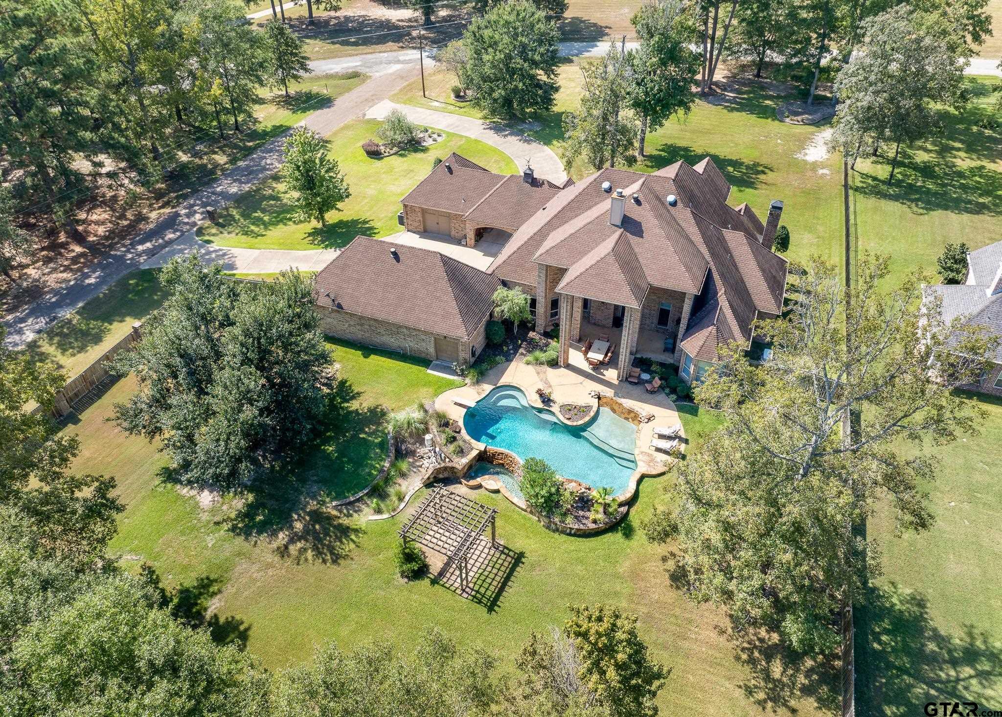 an aerial view of a house with swimming pool and large trees