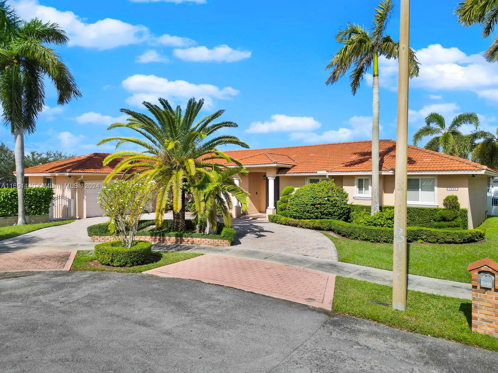 a view of a house with a yard and palm trees