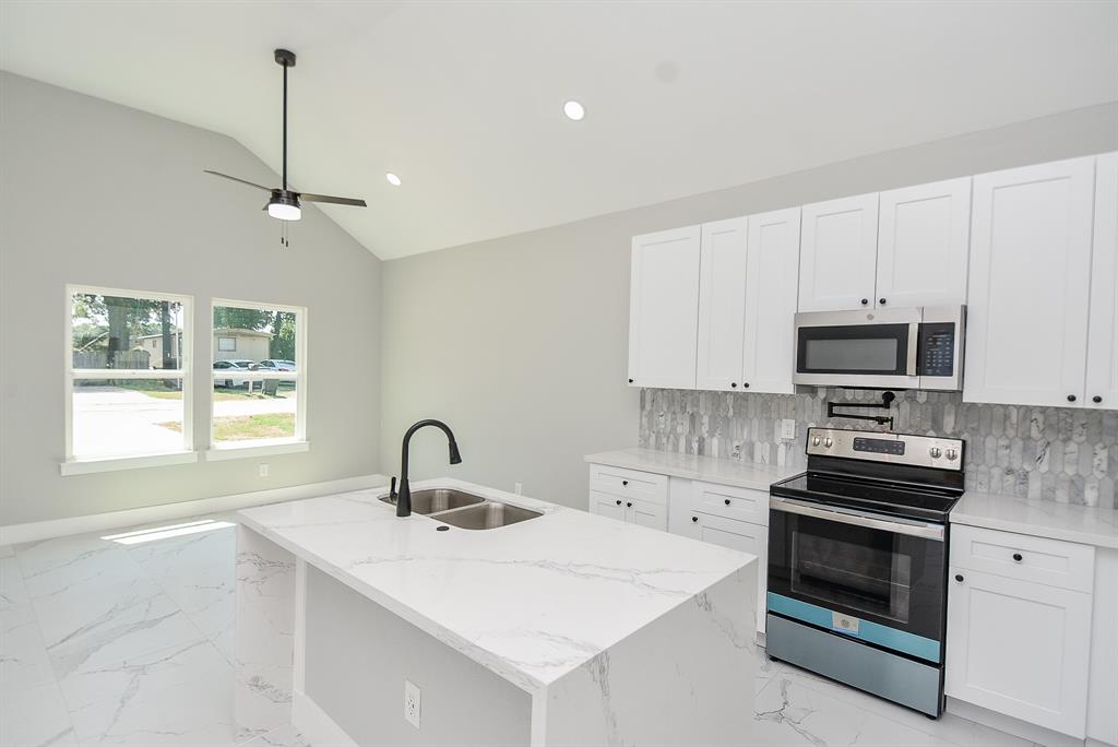 a kitchen with stainless steel appliances a stove a sink and white cabinets