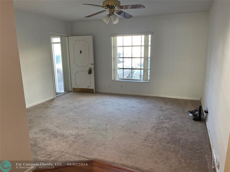 an empty room with a ceiling fan and a window