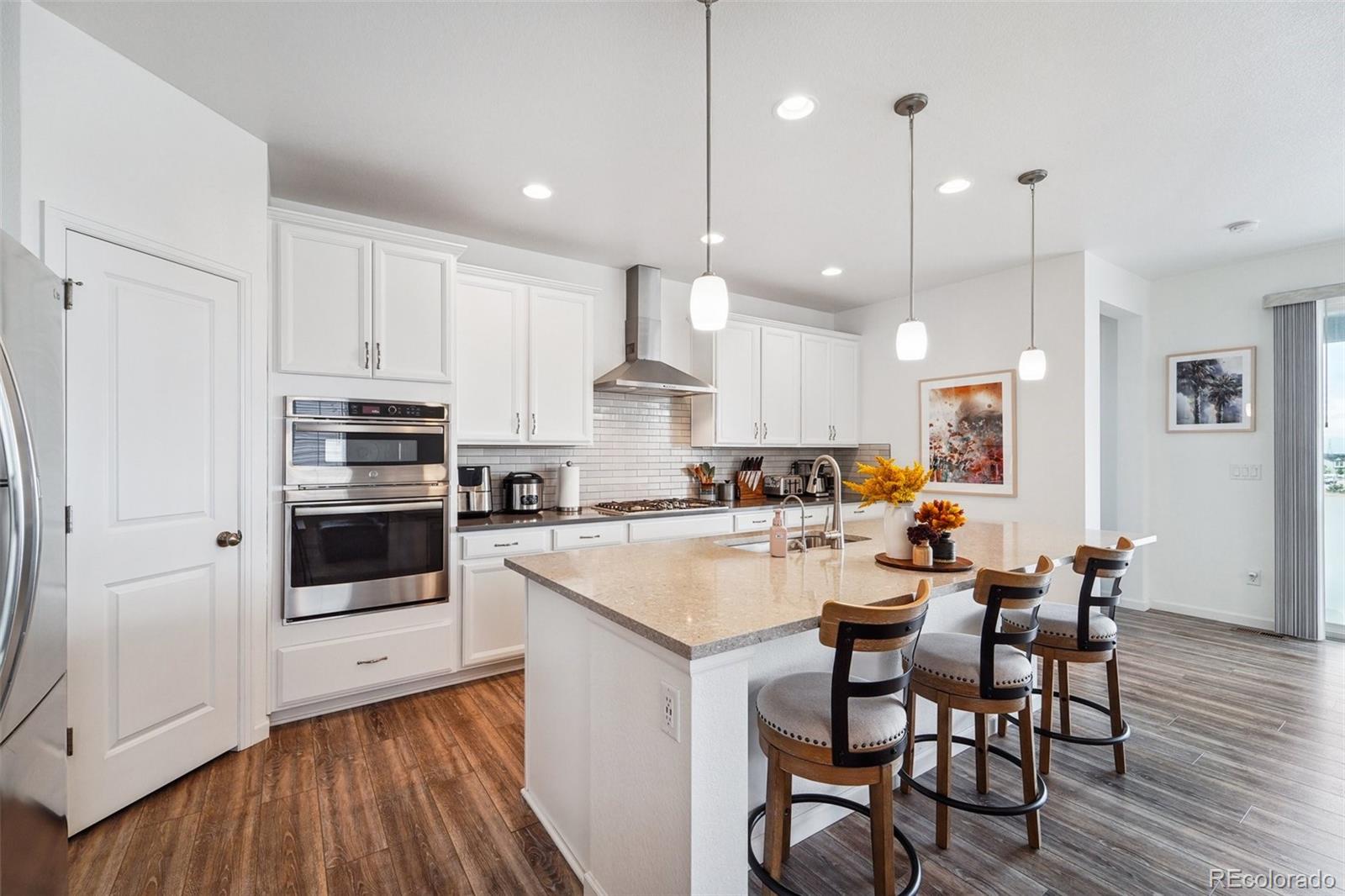 a large kitchen with cabinets chairs and wooden floor