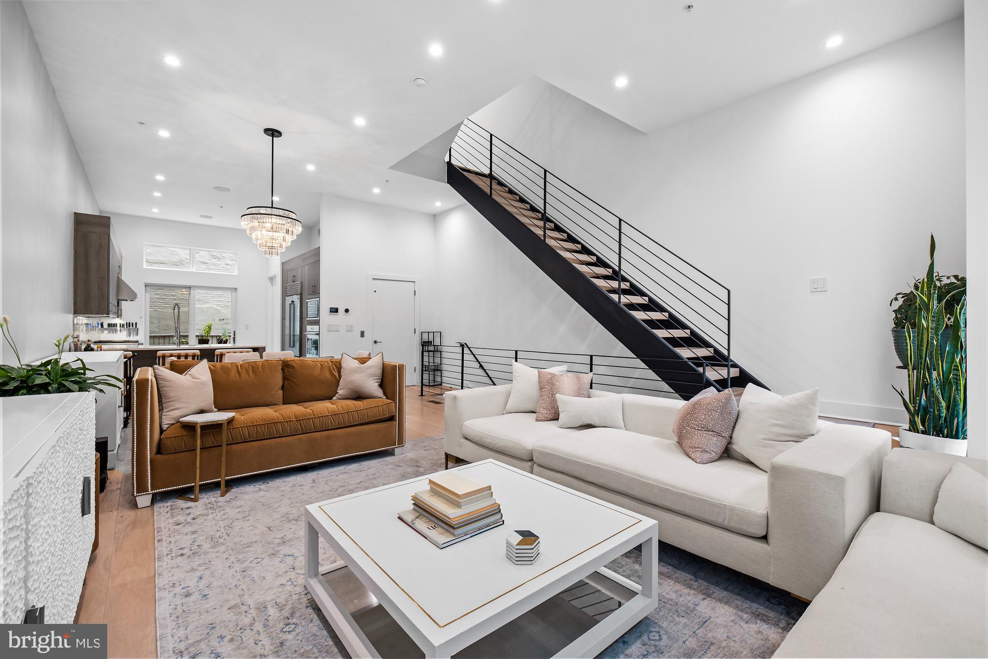 a living room with furniture kitchen view and a chandelier