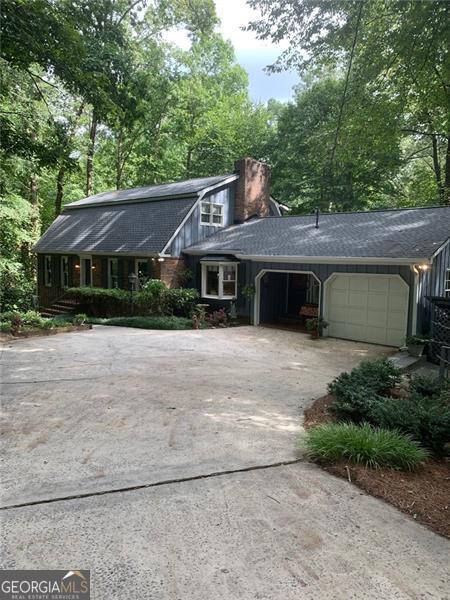 a front view of a house with a garden and trees