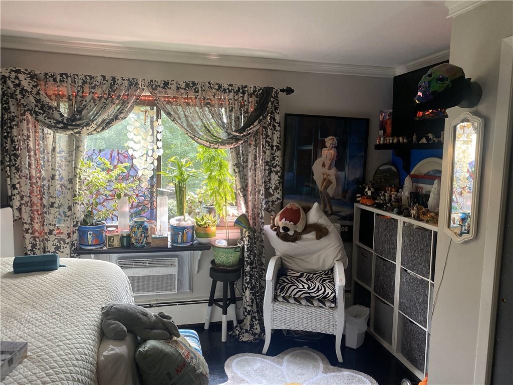 Bedroom featuring a wall mounted AC, baseboard heating, and crown molding