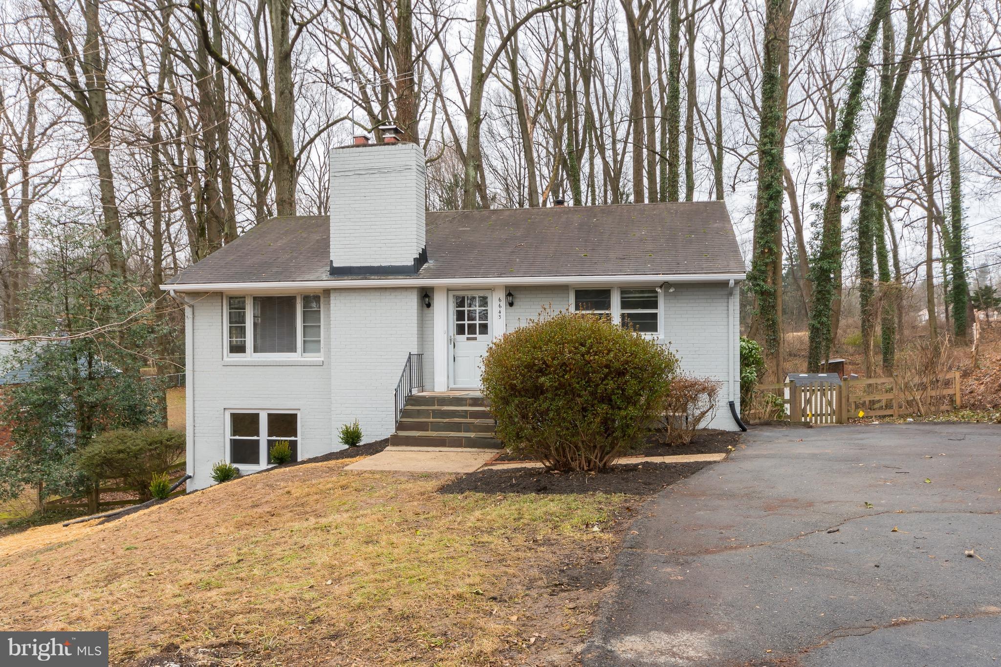 a front view of a house with a garden and trees