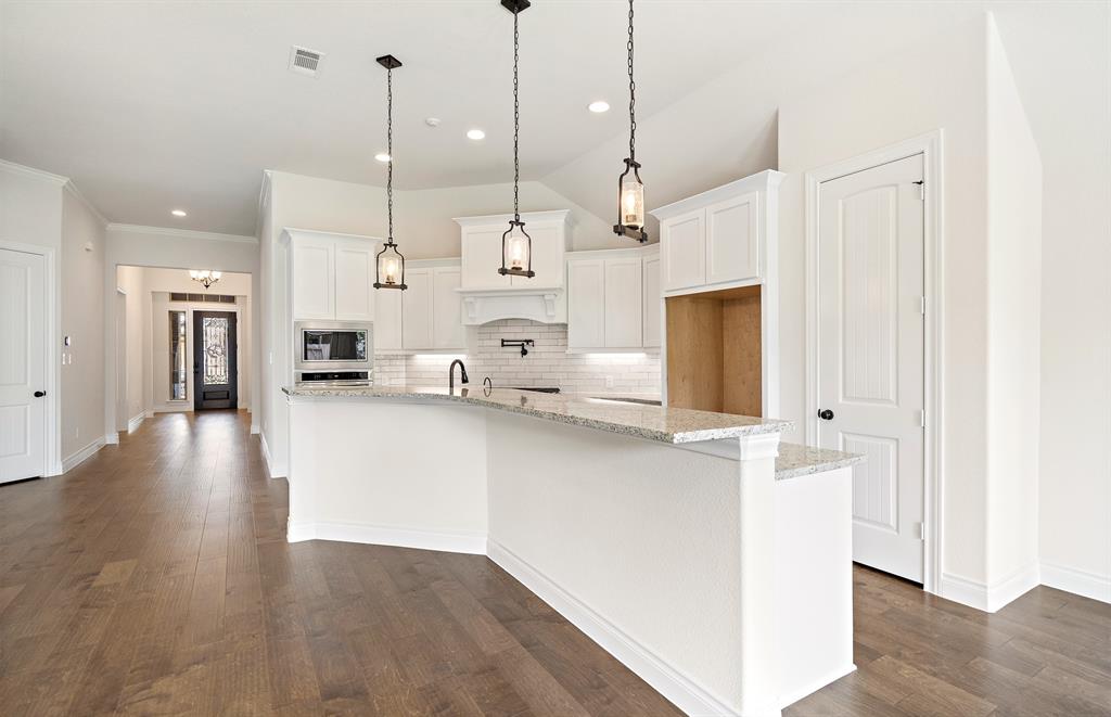 a open kitchen with stainless steel appliances kitchen island wooden floors granite counter tops and white cabinets