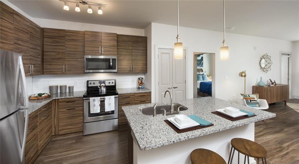 a kitchen with granite countertop kitchen island stainless steel appliances a sink stove and refrigerator