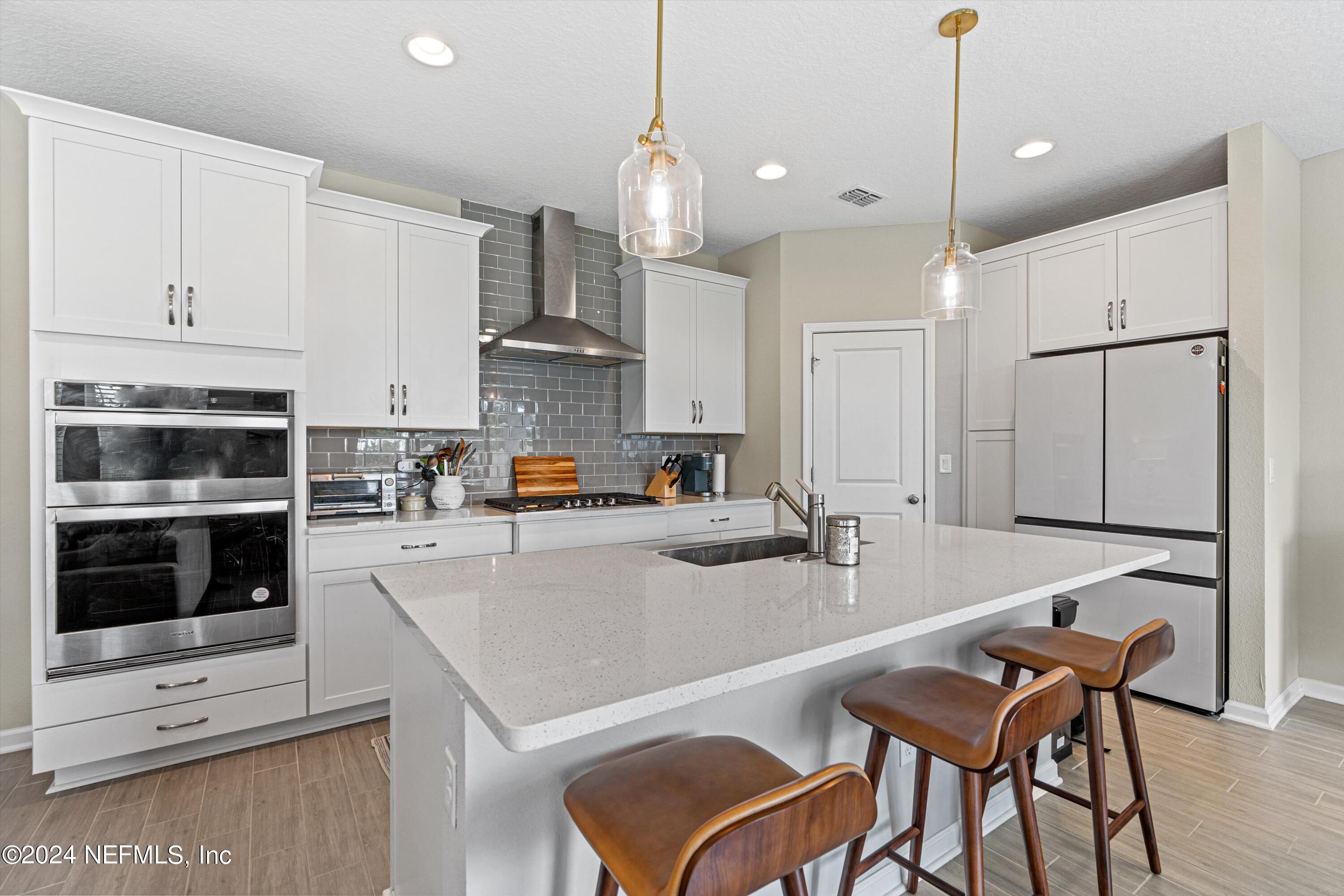 a kitchen with stainless steel appliances granite countertop a stove top oven a refrigerator a sink and a dining table with granite countertop chairs