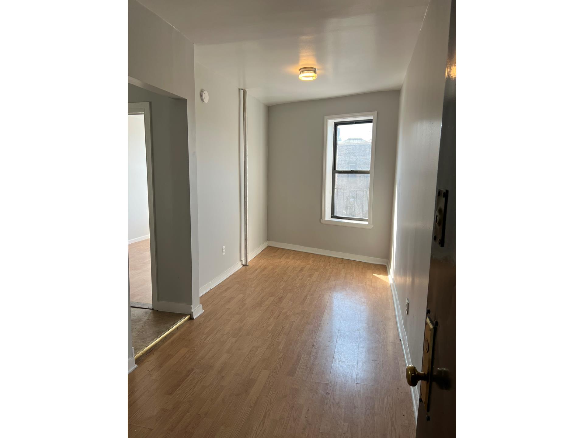 a view of an empty room with wooden floor and a window