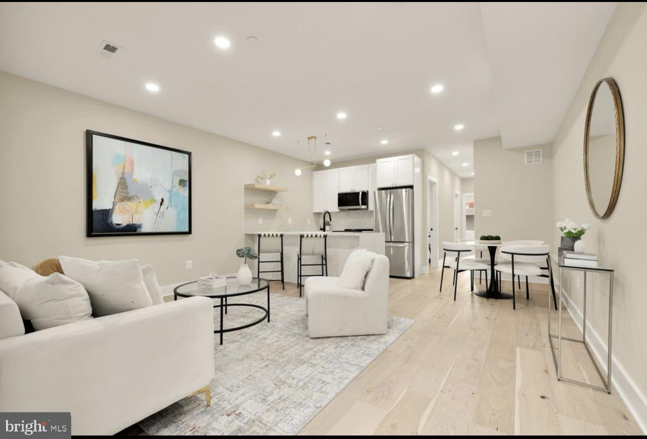 a living room with furniture kitchen view and a large window