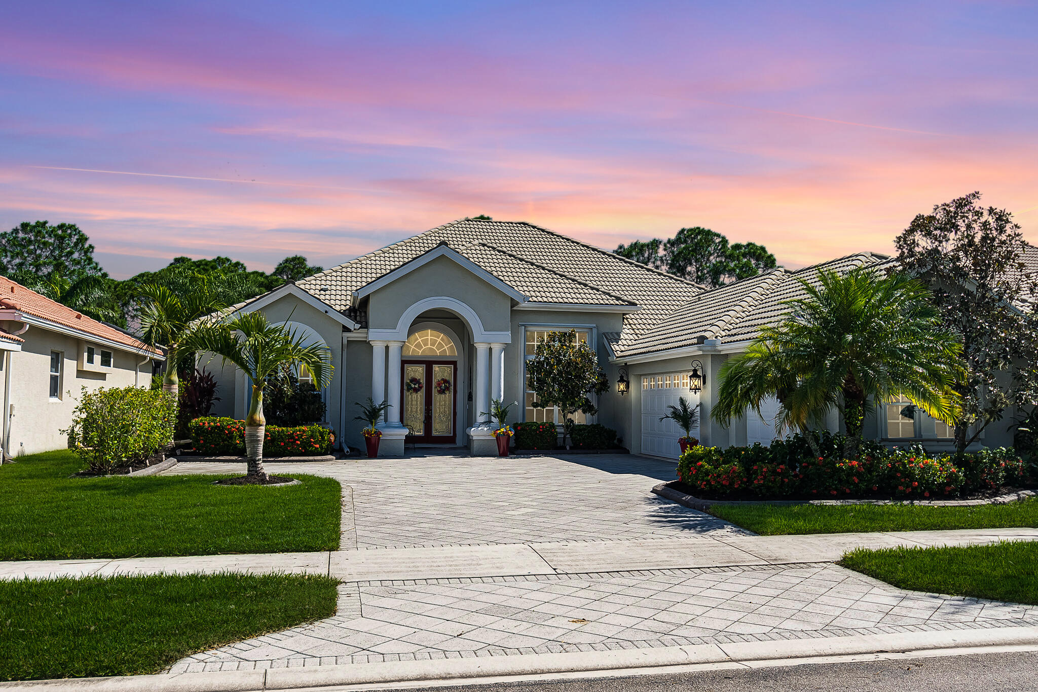 a view of a white house with a big yard and potted plants