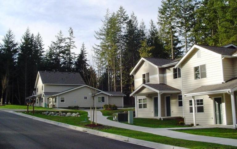 a view of a white house next to a yard and large trees