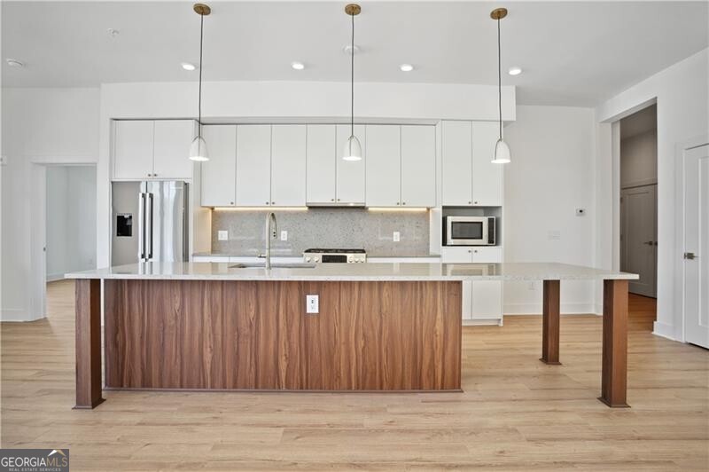 a view of a kitchen with stainless steel appliances granite countertop a refrigerator a sink and wooden floors