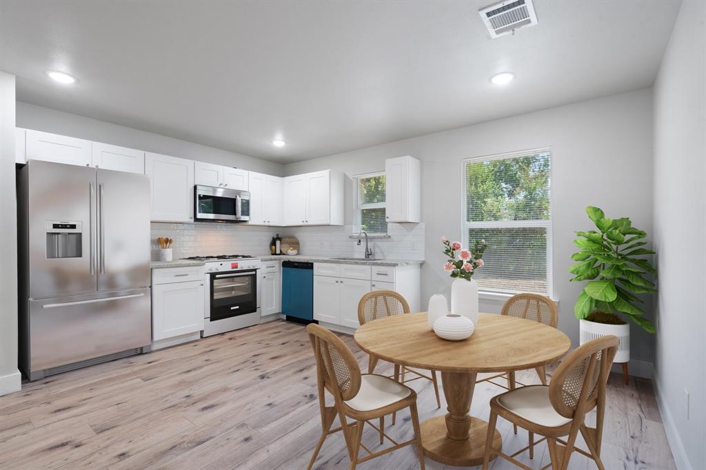 a kitchen with stainless steel appliances a dining table chairs microwave and stove