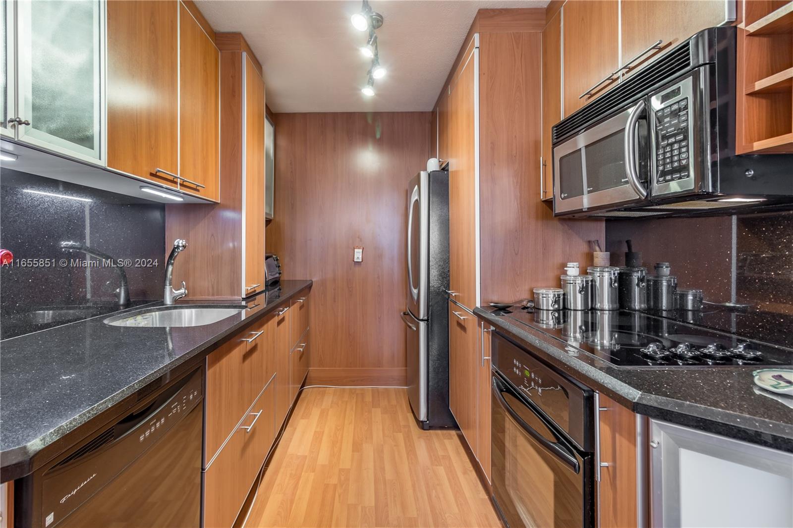 a kitchen with stainless steel appliances granite countertop a sink a stove and a wooden cabinets