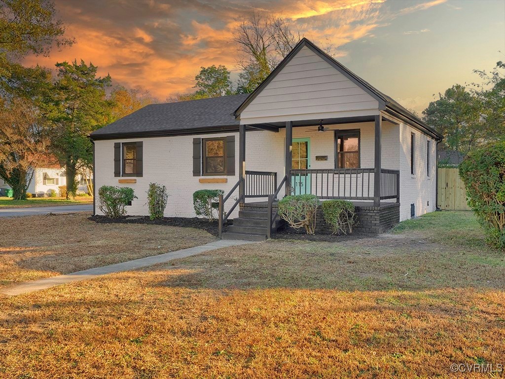 View of front of house featuring a lawn and covere