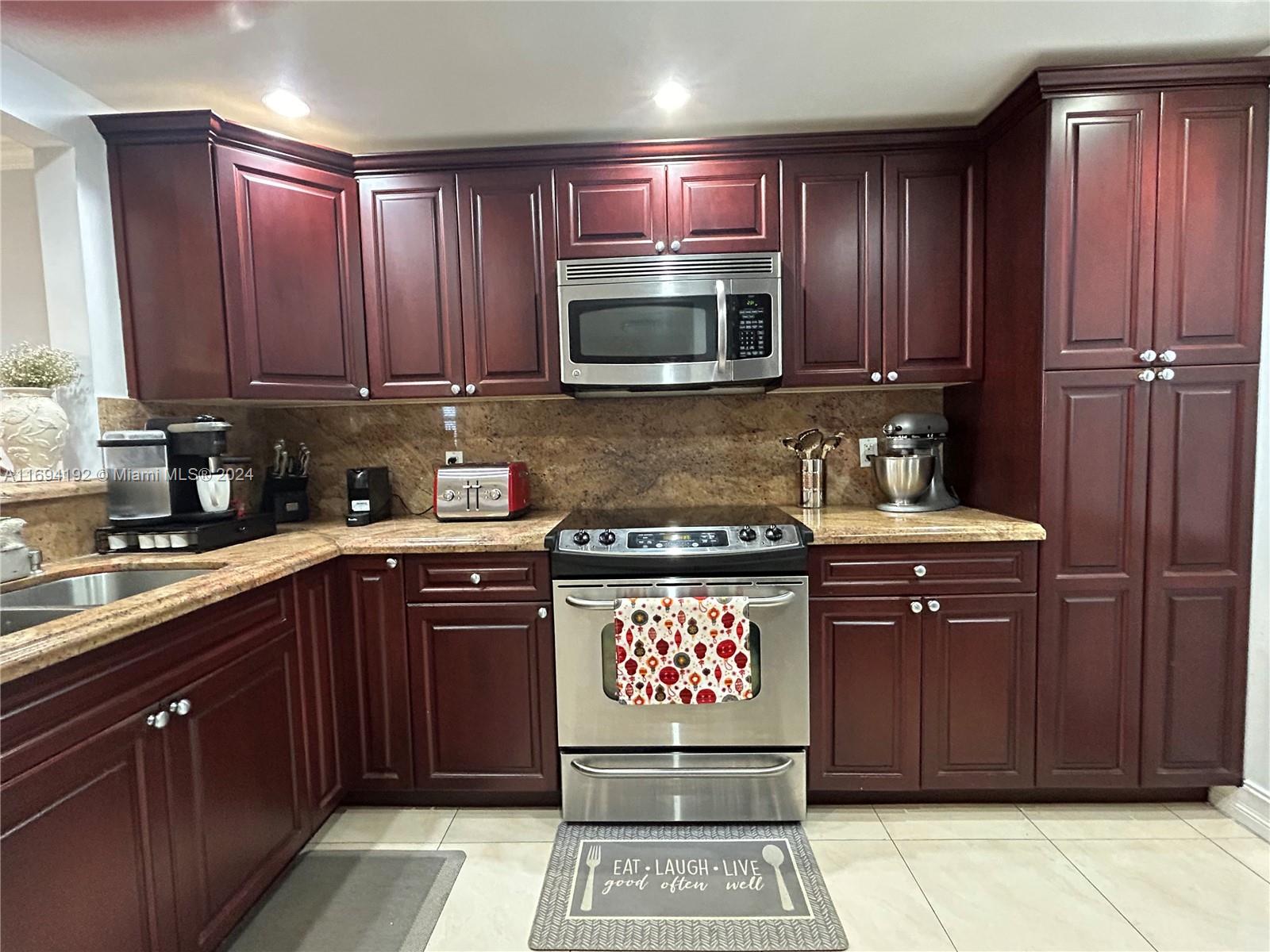 a kitchen with stainless steel appliances granite countertop wooden cabinets a stove top oven a sink and dishwasher