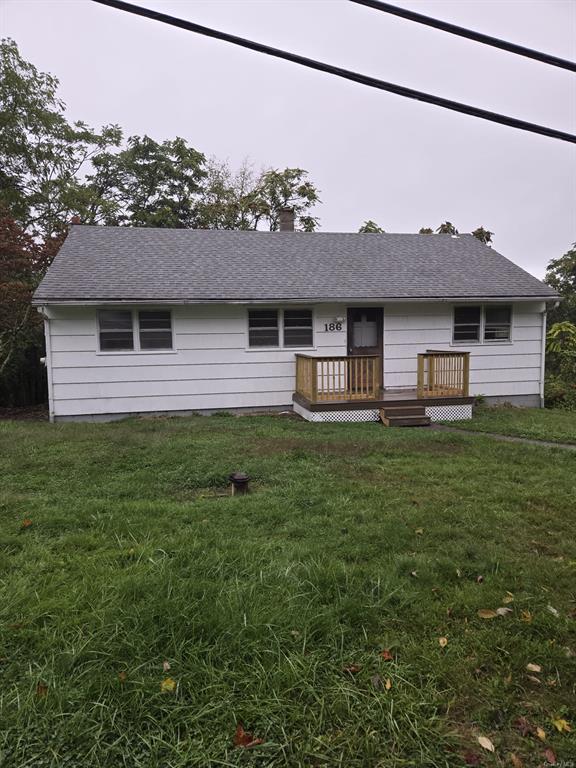 View of front of house featuring a wooden deck and a front lawn