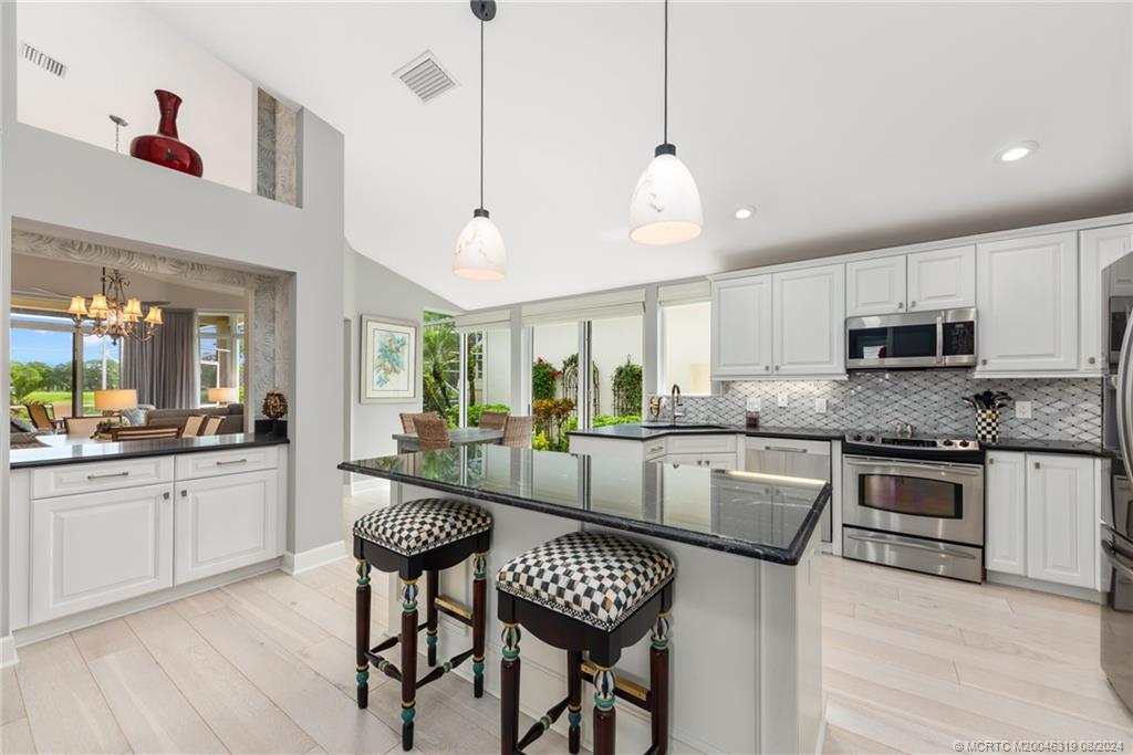 a large kitchen with granite countertop lots of counter space white cabinets and stainless steel appliances