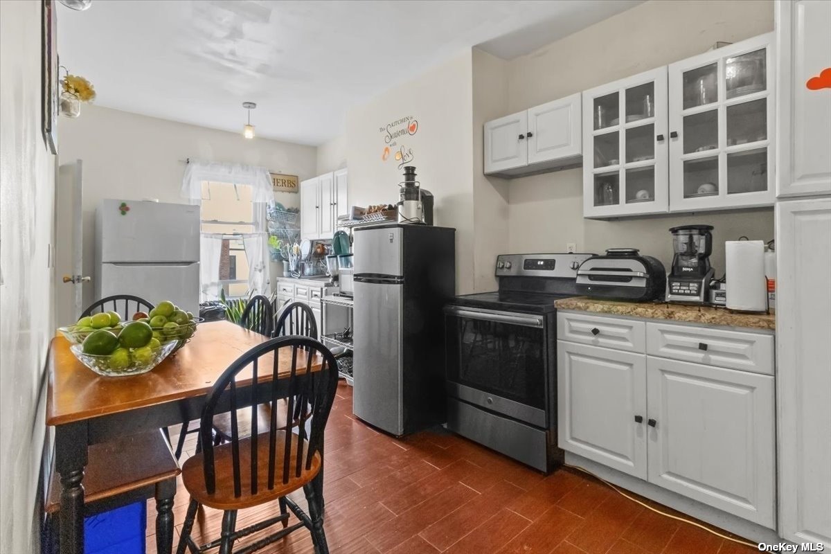 a kitchen with stainless steel appliances kitchen island granite countertop a dining table chairs and a refrigerator